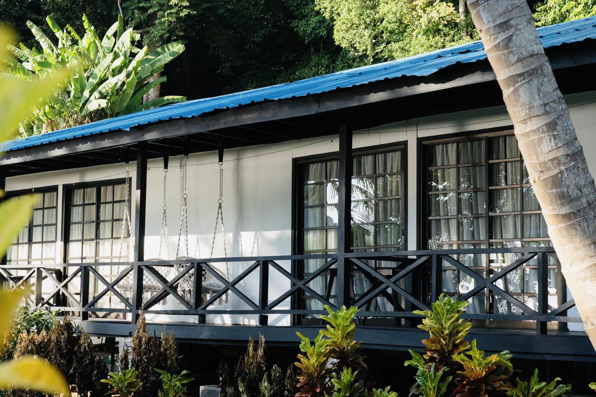 Blue-roofed chalet exterior with veranda and hanging chairs at The One Tenggol